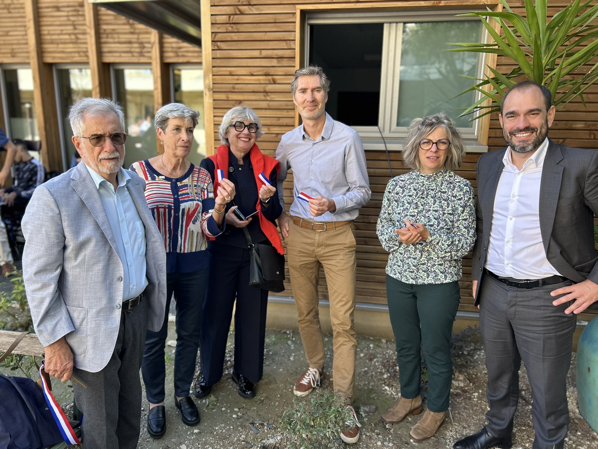 Jean-Bernard Dubois, Laurence Gélinotte, Mathieu Pardell et plusieurs invités posant devant le bâtiment rénové de l'IEM La Cardabelle lors de l'inauguration de l'extension, avec des rubans tricolores à la main.